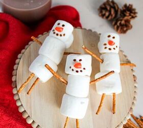 cute and easy marshmallow snowmen for the holidays, Cute marshmallow snowmen on a wooden stand surrounded by pretzel marshmallows and a cup of hot chocolate