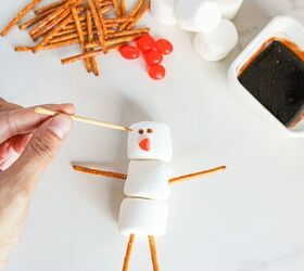 cute and easy marshmallow snowmen for the holidays, Using a toothpick dipped in chocolate syrup to draw the snowman s eyes