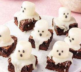 halloween brownies easy ghost brownies, Fudgy chocolate brownies cut into squares topped with white marshmallow ghosts and candy eyes on a parchment lined tray