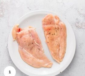 easy chicken roulade recipe with spinach sundried tomatoes gf, Two raw chicken breasts perfect for making Chicken Roulade with sundried tomatoes and spinach are seasoned with salt and black pepper on a white plate set on a light colored textured surface