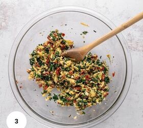 easy chicken roulade recipe with spinach sundried tomatoes gf, A clear glass bowl filled with a vibrant mix of chopped spinach sundried tomatoes shredded cheese and seasonings A wooden spoon rests inside the bowl stirring the perfect filling for a delicious Chicken Roulade
