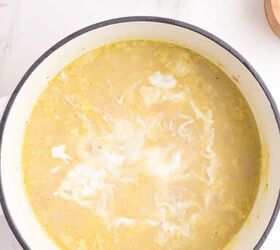 loaded potato soup, A pot of creamy soup with white swirls on top sits on a light marble surface A small bowl of chopped green onions is nearby for garnish