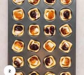 cranberry brie puff pastry bites gluten free, A muffin tin filled with unbaked pastry cups each holding creamy Brie cheese and either cranberry or orange fruit jam arranged in neat rows on a light surface