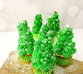 easy christmas tree cupcakes to brighten holidays, Finished Christmas tree cupcakes with green frosting white star toppers and powdered sugar snow arranged on a wooden board