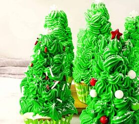 easy christmas tree cupcakes to brighten holidays, Close up of Christmas tree cupcakes decorated with piped green frosting red and white ornaments and snowflake sprinkles