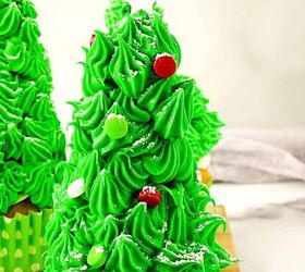 easy christmas tree cupcakes to brighten holidays, Single Christmas tree cupcake decorated with piped green frosting red and green candies and a white star topper with more cupcakes in the background
