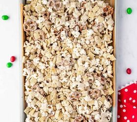 christmas crunch recipe easy holiday snack mix, Overhead shot of Christmas popcorn mix spread on parchment paper with festive sprinkles and candies
