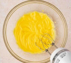 rumchata pudding shots recipe easy and festive with 5 ingredients, A mixing bowl with instant vanilla pudding mix and cold milk being whisked together using a hand mixer until smooth and lump free creating a creamy base for the pudding shots