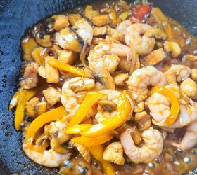 easy and delicious chicken and shrimp stir fry recipe, Shrimp chicken mushrooms and bell peppers simmering in sauce inside a hot wok
