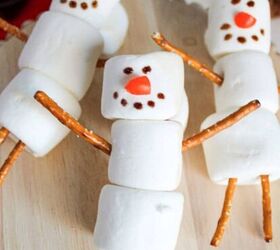 easy and delicious chicken and shrimp stir fry recipe, Three marshmallow snowmen with pretzel stick arms and legs arranged on a wooden stand surrounded by a red towel hot cocoa and pinecones