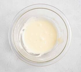 best eggnog pound cake rum eggnog glaze, A clear glass bowl containing a small amount of smooth white batter or sauce sits on a light textured surface