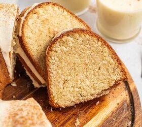 best eggnog pound cake rum eggnog glaze, A close up of sliced bundt cake with white icing arranged on a wooden board Two forks and glasses of creamy eggnog are in the background The cake is moist with a light golden brown crumb