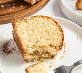 best eggnog pound cake rum eggnog glaze, A close up of a slice of moist eggnog pound cake on a white plate with a fork holding a bite sized piece More cake slices and crumbs are in the background on another plate and a wooden board