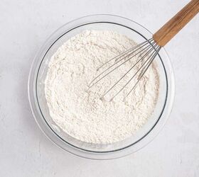 best eggnog pound cake rum eggnog glaze, A glass bowl filled with flour mixture is being stirred with a metal whisk that has a wooden handle set on a light colored surface