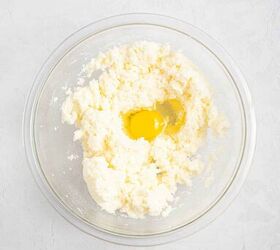 best eggnog pound cake rum eggnog glaze, A glass mixing bowl with creamed butter and sugar and a raw egg cracked on top sitting on a light textured surface