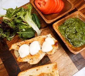 pesto chicken sandwich, Sauteed chicken breast with mozzarella cheese and fresh basil served with tomato slices and green pesto on a wooden platter