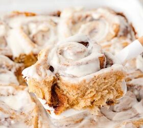 cinnamon rolls with fresh milled flour, Close up of swirled cinnamon rolls with white icing one roll lifted on a spatula