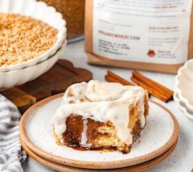 cinnamon rolls with fresh milled flour, Cinnamon roll with white icing on a speckled plate cinnamon sticks and flour in background