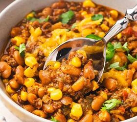 best slow cooker chili with beef and pinto beans, Close up of spicy beef chili in a bowl with beans corn and fresh green toppings