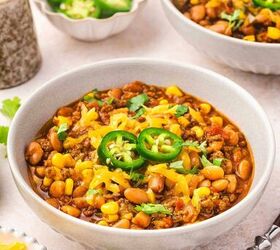best slow cooker chili with beef and pinto beans, Bowl of thick hearty chili with ground beef beans corn and colorful toppings ready to eat