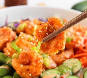 the best bang bang shrimp bowl ready in 30 minutes, Bang bang shrimp held with chopsticks above a rice bowl