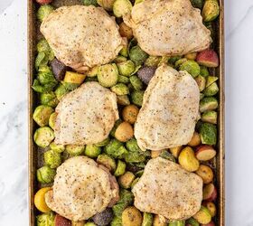 sheet pan chicken thighs, Raw seasoned chicken thighs on top of brussels sprouts and potatoes on a sheet pan