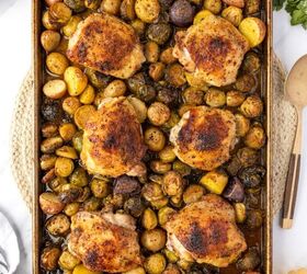 sheet pan chicken thighs, Sheet Pan Chicken Thighs cut on a sheet pan with roasted potatoes and brussels sprouts ready to serve with plates around the table