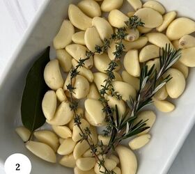 garlic confit with thyme and rosemary, Peeled garlic cloves in a white dish prepared for garlic confit are garnished with a bay leaf thyme and rosemary A white circle with the number 2 appears in the bottom left corner