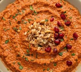 garlic confit with thyme and rosemary, A bowl of muhammara dip made from a classic muhammara recipe garnished with chopped walnuts parsley and pomegranate seeds displayed on a light colored plate against a white background