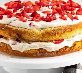 chocolate caramel cake recipe rich moist easy, Strawberry banana layer cake with vanilla sponge whipped cream frosting and fresh chopped strawberries on top displayed on a white cake stand
