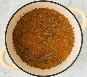 roasted red pepper and tomato soup, A beige Dutch oven filled with seasoned brown broth sits on a light gray textured surface
