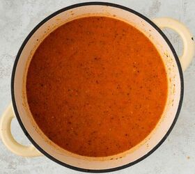 roasted red pepper and tomato soup, A cream colored pot filled with smooth orange red tomato soup viewed from above on a light gray textured surface