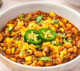easy creamy roasted red pepper gouda soup recipe, Hearty slow cooker beef and pinto bean chili served in a white bowl topped with cheddar jalapeno and cilantro