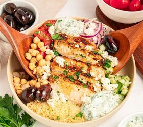 mediterranean chicken couscous bowl, A vibrant Mediterranean chicken bowl featuring grilled chicken slices chickpeas kalamata olives cherry tomatoes cucumber red onion couscous tzatziki sauce and crumbled feta cheese served with wooden salad servers