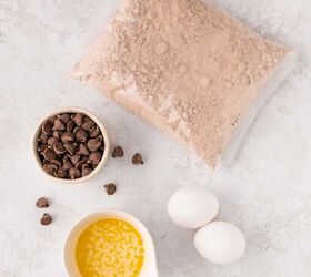 easy red velvet cake mix brownies, A bag of red velvet cake mix a small bowl of chocolate chips two eggs and a small bowl of melted butter arranged on a light colored surface