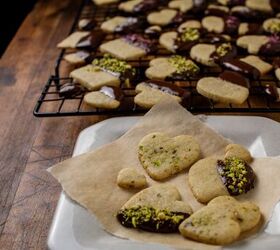 pistachio cookies dipped in dark chocolate, chocolate dipped pistachio cookies garnished with crushed pistachio s rose petals and sea salt