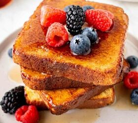 air fryer french toast easy ready in minutes, A stack of French toast topped with fresh raspberries blackberries and blueberries drizzled with syrup served on a white plate with extra berries on the side