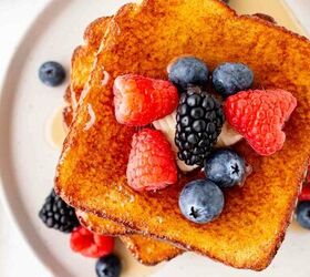 air fryer french toast easy ready in minutes, A stack of golden brown French toast topped with fresh raspberries blackberries blueberries and a dollop of cream or butter served on a white plate with syrup drizzled around