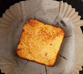 air fryer french toast easy ready in minutes, A single slice of toasted bread with golden brown edges sits on parchment paper inside a round black air fryer basket