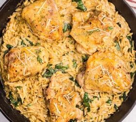 greek beef meatballs in tomato sauce soutzoukakia, A cast iron skillet filled with creamy chicken orzo bake wilted spinach and five golden brown chicken thighs garnished with grated cheese and herbs sits on a light surface near a striped towel