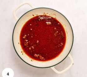 greek beef meatballs in tomato sauce soutzoukakia, A white pot with handles contains Soutzoukakia Greek beef meatballs in a rich red tomato sauce with small chunks of meat sitting on a light colored marble surface The number 4 appears in a white circle in the bottom left corner