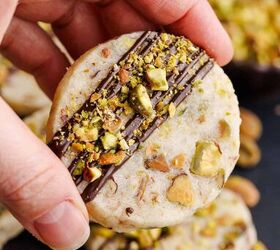 pistachio shortbread cookies, Pistachio Shortbread Cookies up close with chocolate drizzle and crushed nuts being picked up