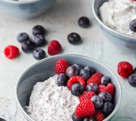 easy high protein greek yogurt bowl with chia seeds berries, Low angle shot of a Greek Yogurt Protein bowl The small bowl is filled with creamy white yogurt mixed with chia seeds On top are fresh blueberries and raspberries In the background are two more Greek yogurt breakfast bowls Fresh raspberries and blueberries are scattered around