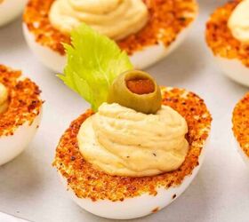 the best bloody mary deviled eggs recipe easy brunch appetizer, Macro shot of deviled eggs coated with Taj n and topped with celery olives and cherry tomatoes