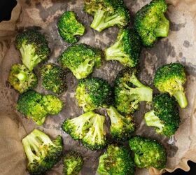 air fryer broccoli, Broccoli florets cooked and slightly browned on parchment paper inside a black air fryer basket