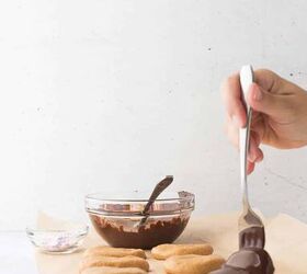 cashew butter reese s eggs gluten free and dairy free recipe, hand using the fork to place the chocolate dipped cashew butter reese egg onto a parchment lined baking sheet