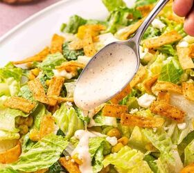 easy mexican caesar salad recipe with creamy lime dressing, A spoon drizzling creamy lime dressing over a Mexican Caesar salad with romaine lettuce Cotija cheese roasted corn and tortilla strips on a platter