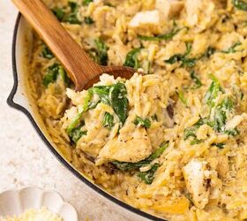 lemon chicken orzo pasta one pan, A creamy chicken and spinach orzo dish is being stirred with a wooden spoon in a skillet Grated cheese is in a small bowl nearby and a lemon wedge is visible in the background