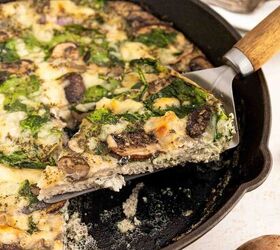 easy egg white frittata fluffy high protein, A slice of vegetable frittata with spinach and mushrooms is being lifted from a cast iron skillet The frittata is creamy and dotted with greens and mushrooms with another slice on a plate in the background