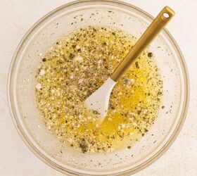 easy egg white frittata fluffy high protein, A glass bowl filled with egg whites seasonings and cracked black pepper with a white spatula featuring a gold handle resting inside The bowl is placed on a light colored surface